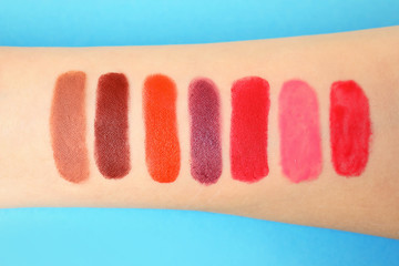 Woman with lipstick swatches on color background, closeup