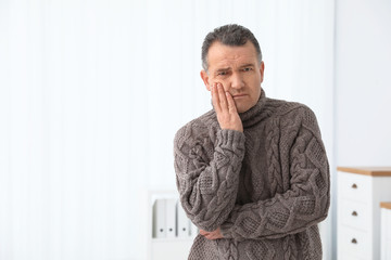 Fototapeta na wymiar Mature man suffering from strong tooth pain at home, space for text