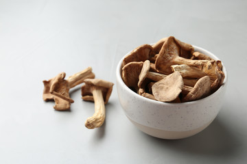 Bowl of dried mushrooms on color background. Space for text