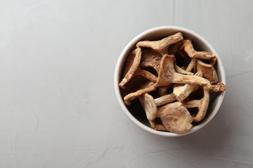 Bowl of dried mushrooms on color background, top view. Space for text