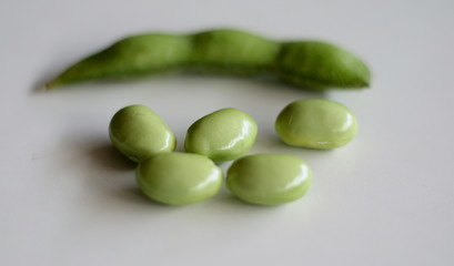 Young soy beans or edamame on wood plate. White background.