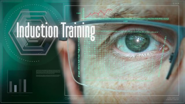 A close up of a businessman eye controlling a futuristic computer system with a Business Induction Training concept.