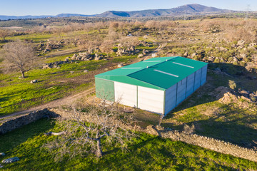 An aerial view of the amazing "Dehesa Extremeña" with a shed for farmland storage in between the trees, boulders and the old stone fence in Extremadura land at west Spain, an amazing landscape  © abriendomundo