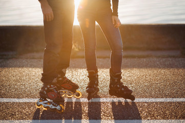 Couple on rollers. Evening ride on roller skates. Shadows and the silhouette. Evening sunset sun and glare.