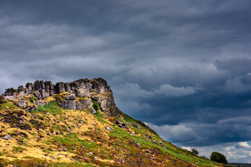 Dramatic sky over rocky hill.