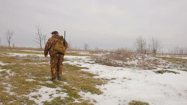 Winter hunting for hares. Hunter With A Catch, Wild Hare. People with Shotgun looking for prey. 
