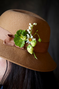 Profile of woman in hat with flowers and strawberry on it