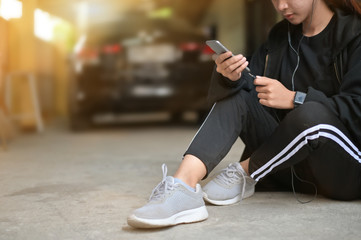 Runner woman using a mobile phone with ear phone pre-running on floor in home.