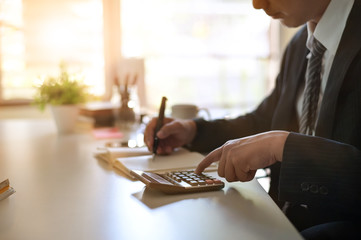 Businessman doing finances and calculate on office desk about cost at home office.