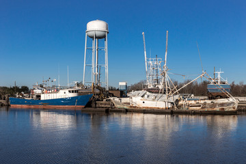 Retired ships tied to wooden dock with calm water and tower