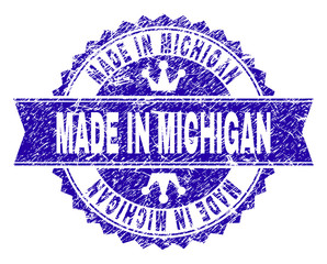 MADE IN MICHIGAN rosette stamp seal imitation with distress texture. Designed with round rosette, ribbon and small crowns. Blue vector rubber print of MADE IN MICHIGAN label with grunge texture.