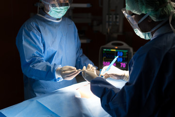 Asian doctor and an assistant in the operating room for surgical venous vascular surgery clinic in...