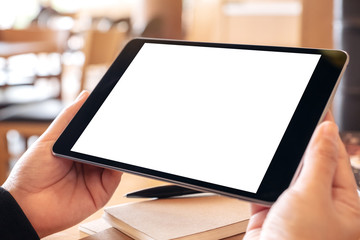 Mockup image of a woman holding black tablet pc with blank white screen horizontally while sitting in cafe