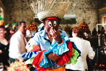 Kerel die een Caraïbisch carnavalskostuum en een grappig masker draagt op een feestje