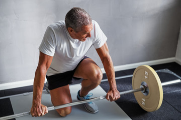 Mature man preparing to lift weights at the gym
