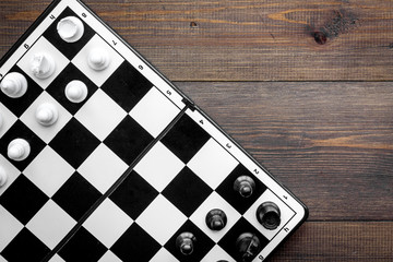 Chess game concept. Chess board with figures on dark wooden background top view copy space