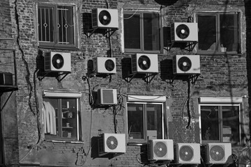 black and white air conditioners on the wall of an old brick building