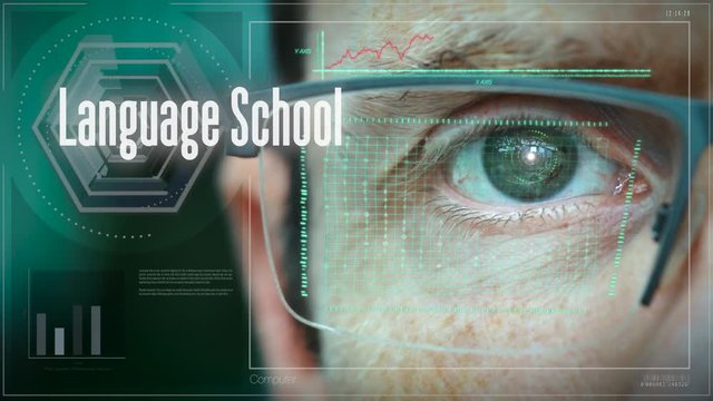 A close up of a businessman eye controlling a futuristic computer system with a Business Language School concept.