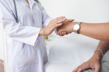 Doctor touching hand of patient to support him when telling diagnosis