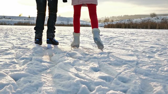 Ice skating teenagers legs on a lake against setting sun - slow motion