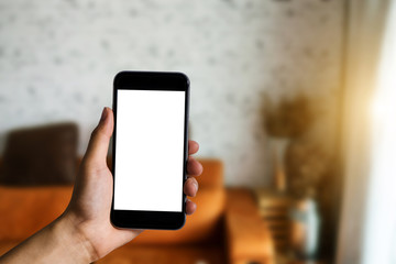 Hand held black phone With a blank white screen in the office in the morning light.