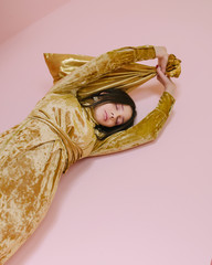 Attractive girl in pink dress in front of pink background. Posing with pink christmas tree. 