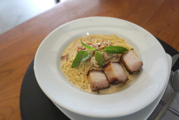 Spaghetti Carbonara sauce with fried chunk pork meat serving on the white plate