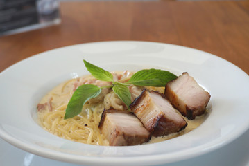 Spaghetti Carbonara sauce with fried chunk pork meat serving on the white plate
