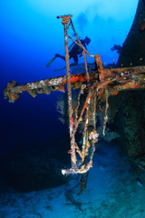 Fototapeta na wymiar SCUBA divers exploring a deep, underwater shipwreck in a clear, tropical ocean