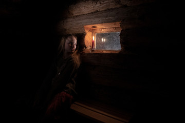 girl by the window in a wooden house with dim light