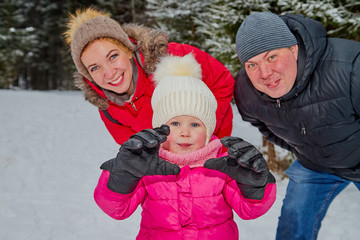 Fototapeta na wymiar Ordinary family walking in a winter forest