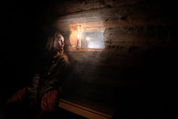 Fototapeta na wymiar girl by the window in a wooden house with dim light
