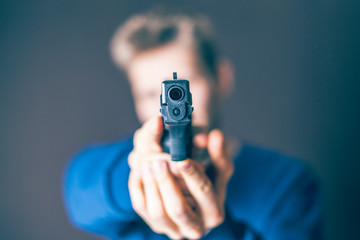male takes aim with the pistol on dark background f