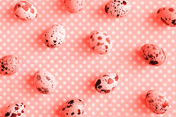 Quail eggs on dotted fabric background toned coral color.