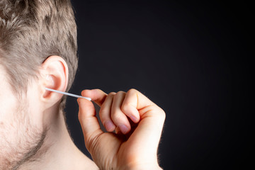 handsome male clean his ear with cotton bud b