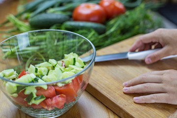 Sliced vegetables for salad,hands are holding a knife
