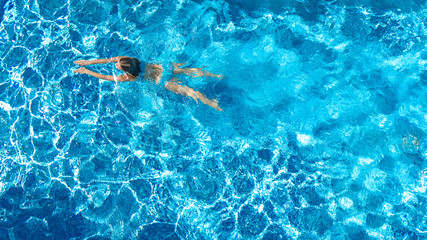 Active girl in swimming pool aerial drone view from above, young woman swims in blue water,...