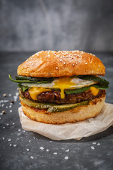 close-up burger with beef cutlet and egg on a wooden board, close-up dark background