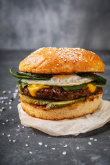 close-up burger with beef cutlet and egg on a wooden board, close-up dark background
