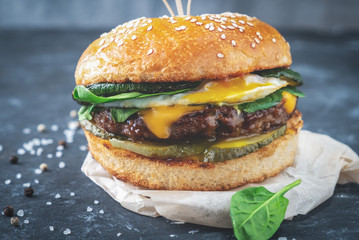 close-up burger with beef cutlet and egg on a wooden board, close-up dark background