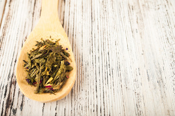 Organic natural green tea on a wooden spoon close-up. Brewed tea on a spoon on the background of white textured table and copy space