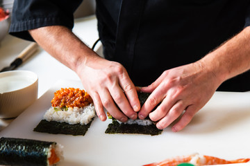 Chef making sushi rolls in the bar