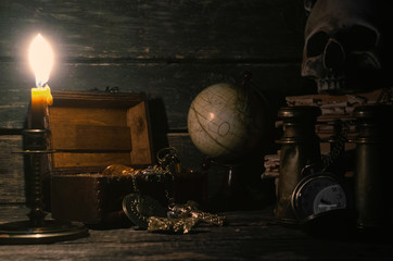 Pirate treasure chest with a gold on a pirate captain table in the light of burning candle...