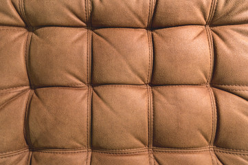 A close-up of a fragment of an expensive brown textile sofa in the room
