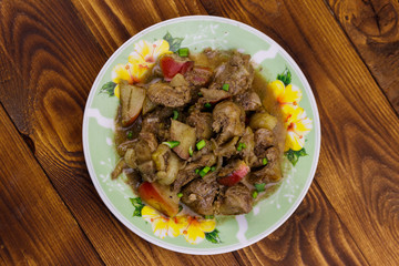 Stewed chicken liver with apple and onion on wooden table