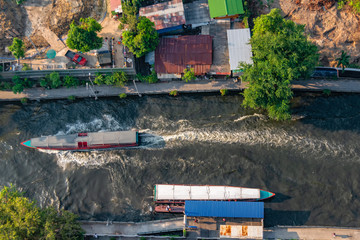 Aerial view of a water bus on a canal in Bangkok, and a construction site along the embankment...