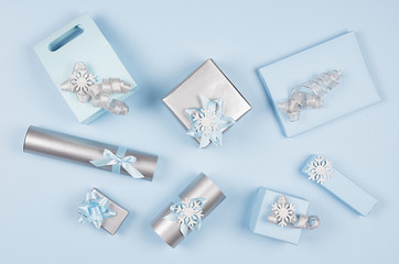 Christmas gift boxes in pastel blue and silver metallic color with ribbons and bows, top view, pattern, festive background.