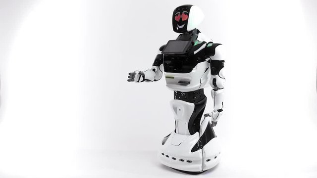 Modern Robotic Technologies. Robot in the bright studio. Android raises and lowers the hand on a white background. Shows evil and good emotions. Looking at camera