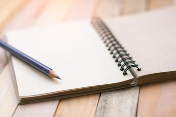 Notepad with pencil on wood board background.