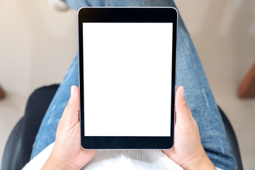 Top view mockup image of a woman holding black tablet pc with blank white screen while sitting on a chair